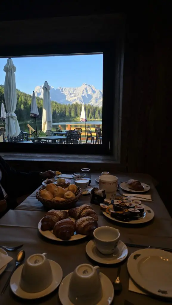 Frühstück in einer Berghütte mit Blick aus dem Fenster auf die Dolomiten