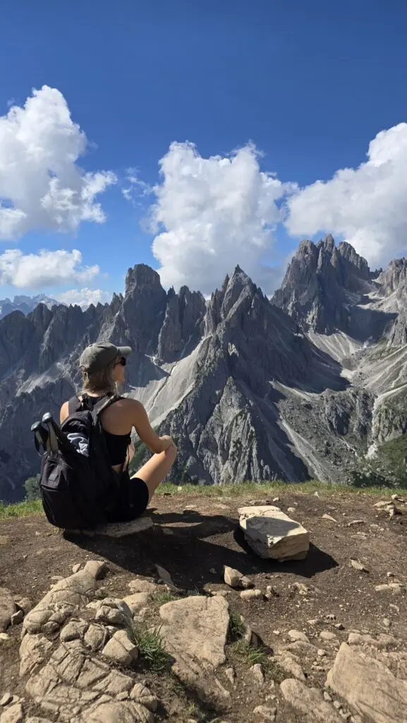 Wanderer ruht auf einem Felsvorsprung mit Blick auf die Gipfel der Dolomiten