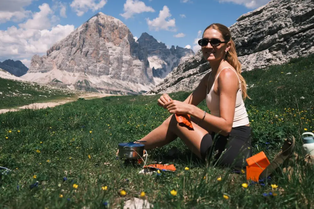 Lächelnder Wanderer entspannt auf einer Almwiese unterhalb der Gipfel der Dolomiten
