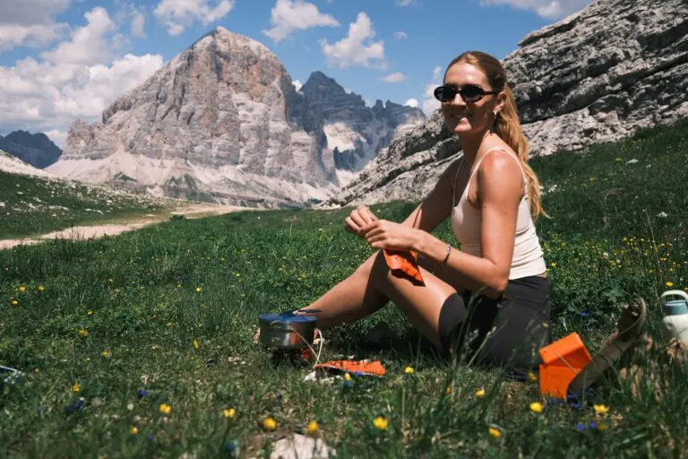 Lächelnder Wanderer entspannt auf einer Almwiese unterhalb der Gipfel der Dolomiten
