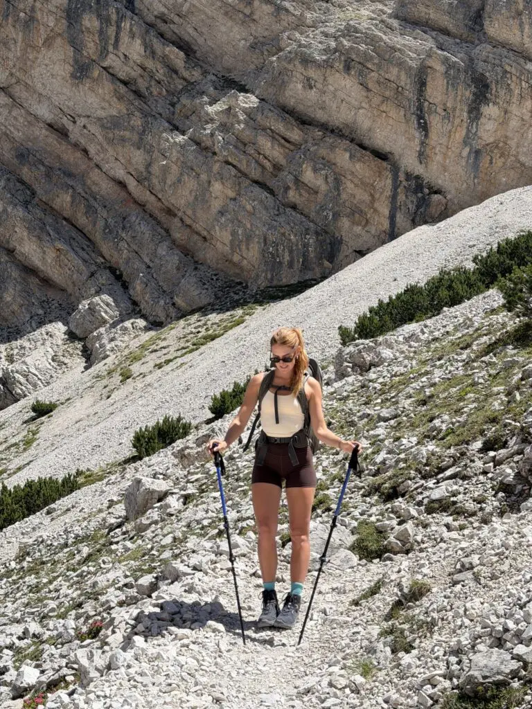 Frau mit Trekkingstöcken auf einem felsigen Weg in den Dolomiten